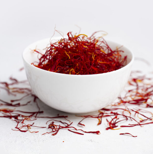 Premium Iranian Saffron threads in a decorative container, showcasing vibrant red color and high quality for culinary and medicinal use.