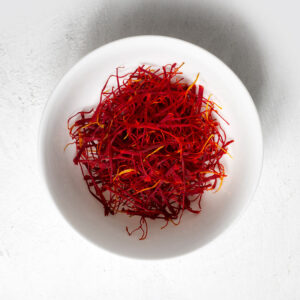 Premium Iranian Saffron threads in a decorative container, showcasing vibrant red color and high quality for culinary and medicinal use.